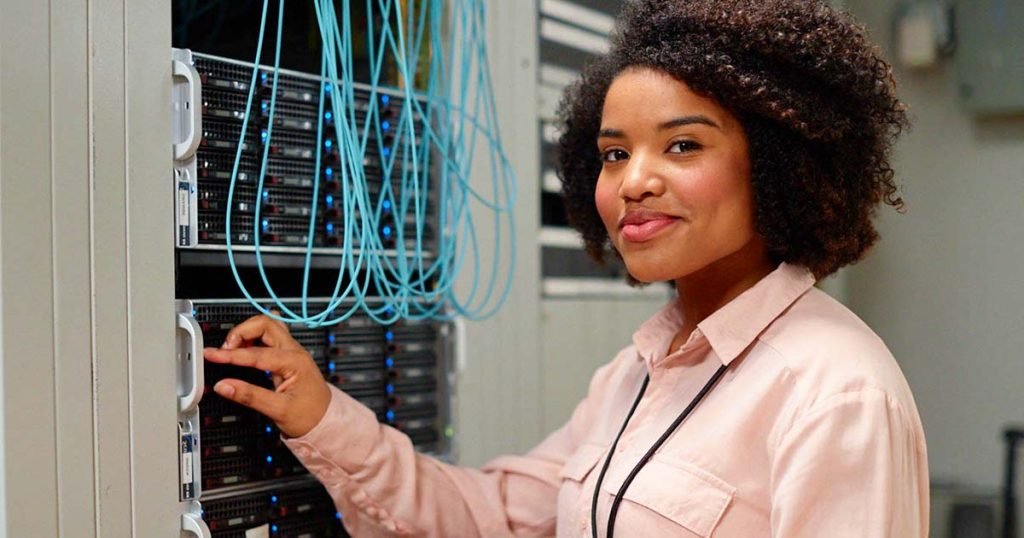 Woman managing network servers with blue cables, representing outsourced network management services for optimized IT infrastructure.